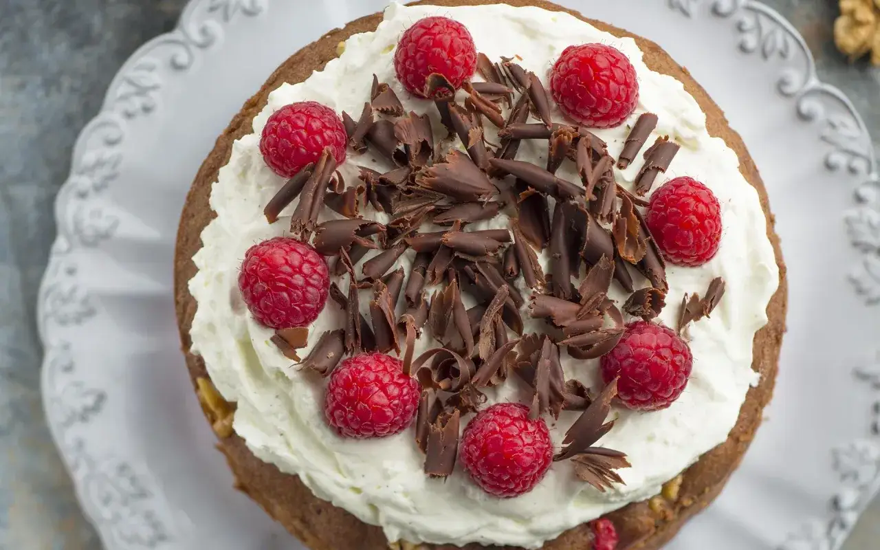 Gâteau au chocolat et mascarpone, garni de framboises fraîches et de copeaux de chocolat. Un délice gourmand !
