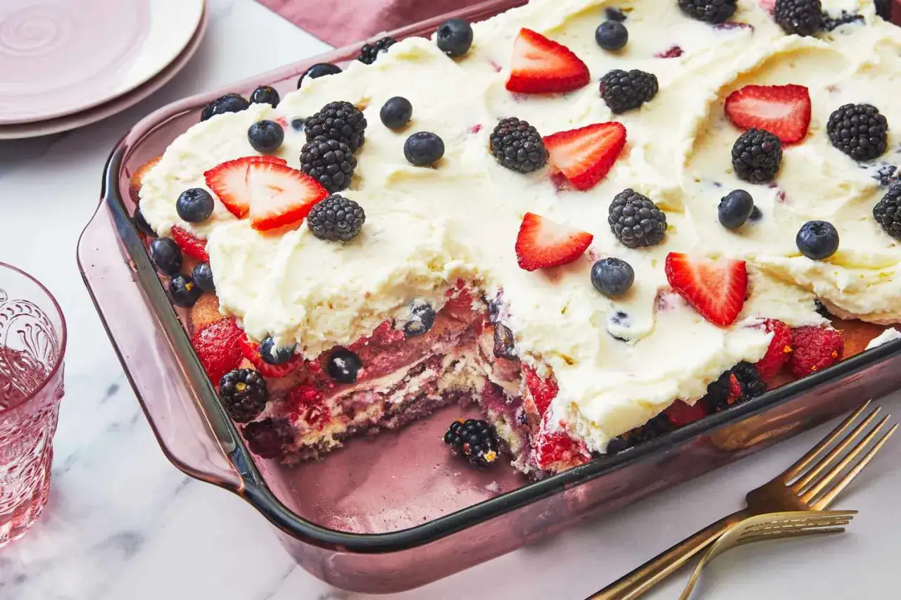 Un délicieux tiramisu fruits, garni de fraises, myrtilles et mûres, dans un plat en verre rose.