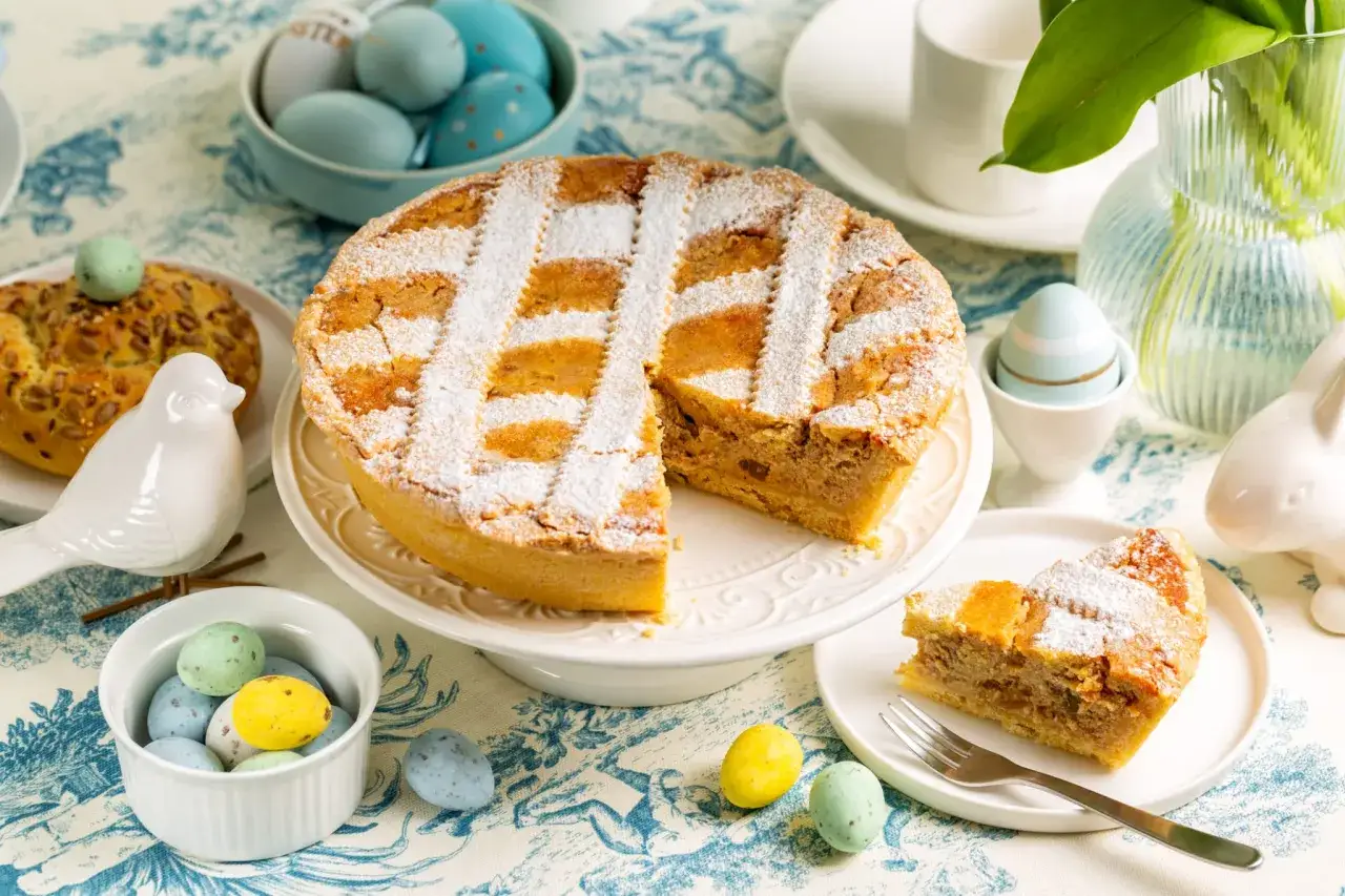 Une délicieuse pastiera napoletana saupoudrée de sucre glace, entourée d'œufs de Pâques colorés et d'une décoration de lapin.