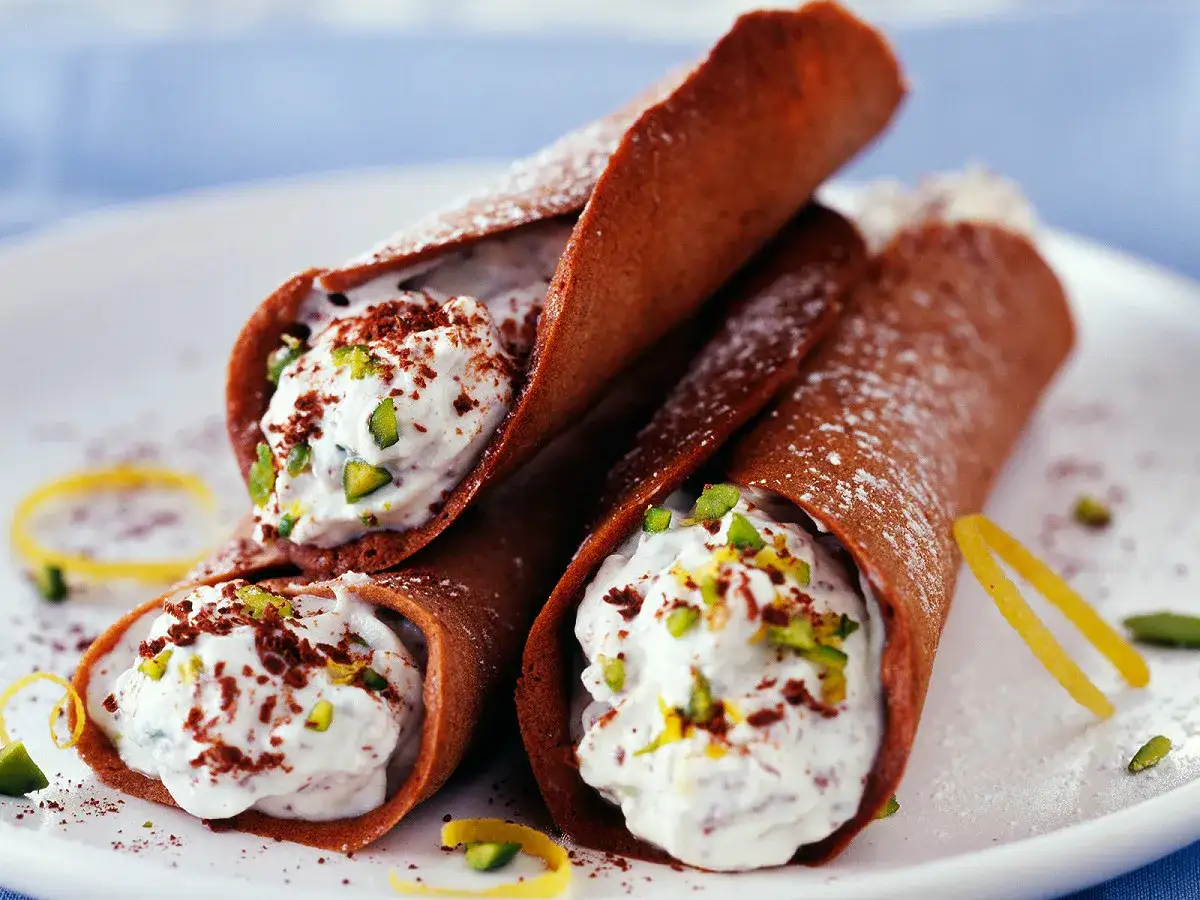 Trois cannoli salés au chocolat, garnis d'une crème onctueuse, de pistaches concassées et de zestes de citron.