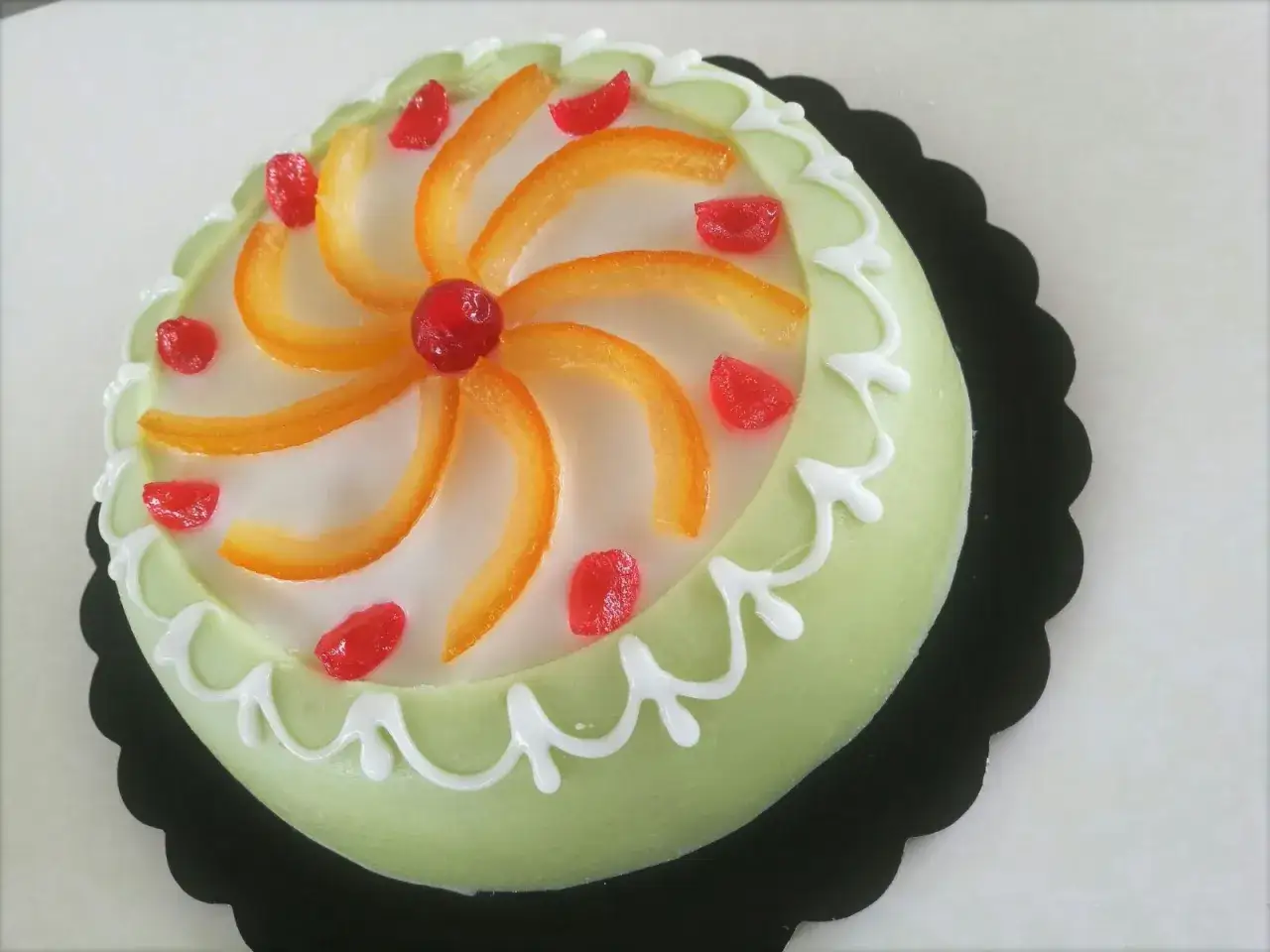 Délicieuse cassata siciliana verte, ornée d'écorces d'orange confites, de cerises rouges et d'un glaçage blanc festonné. Un vrai régal !