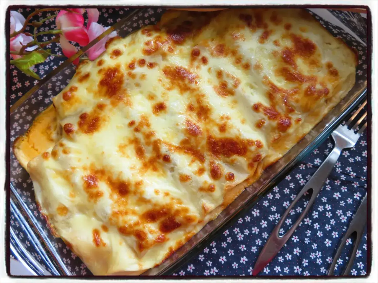 Un plat de cannelloni gratinés, tout juste sorti du four, avec une croûte dorée et fondante. Parfait pour un repas réconfortant.