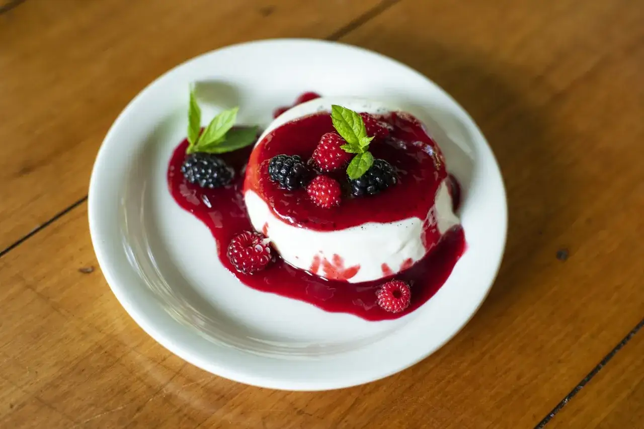 Délicieuse panna cotta avec coulis de fruits rouges et baies fraîches. Un dessert gourmand, mais attention aux panna cotta calories !