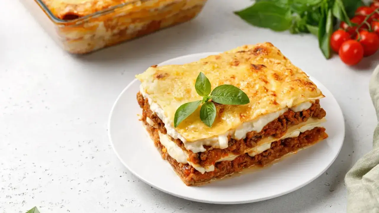 Une part de lasagnes au four, dorée et appétissante, garnie de basilic frais. Parfait pour réchauffer les cœurs.