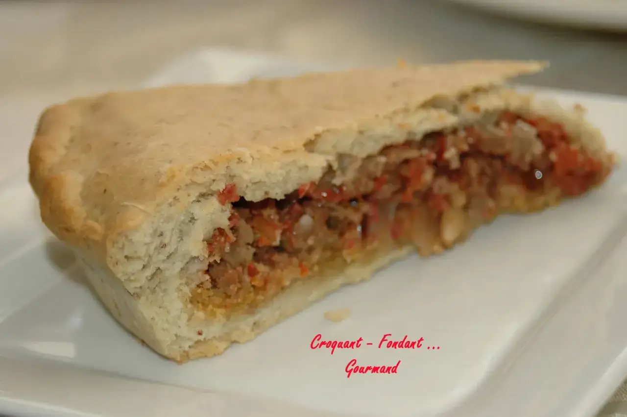 Une part d'impanata siciliana, une tourte sicilienne généreuse et savoureuse, garnie d'une préparation riche et colorée.