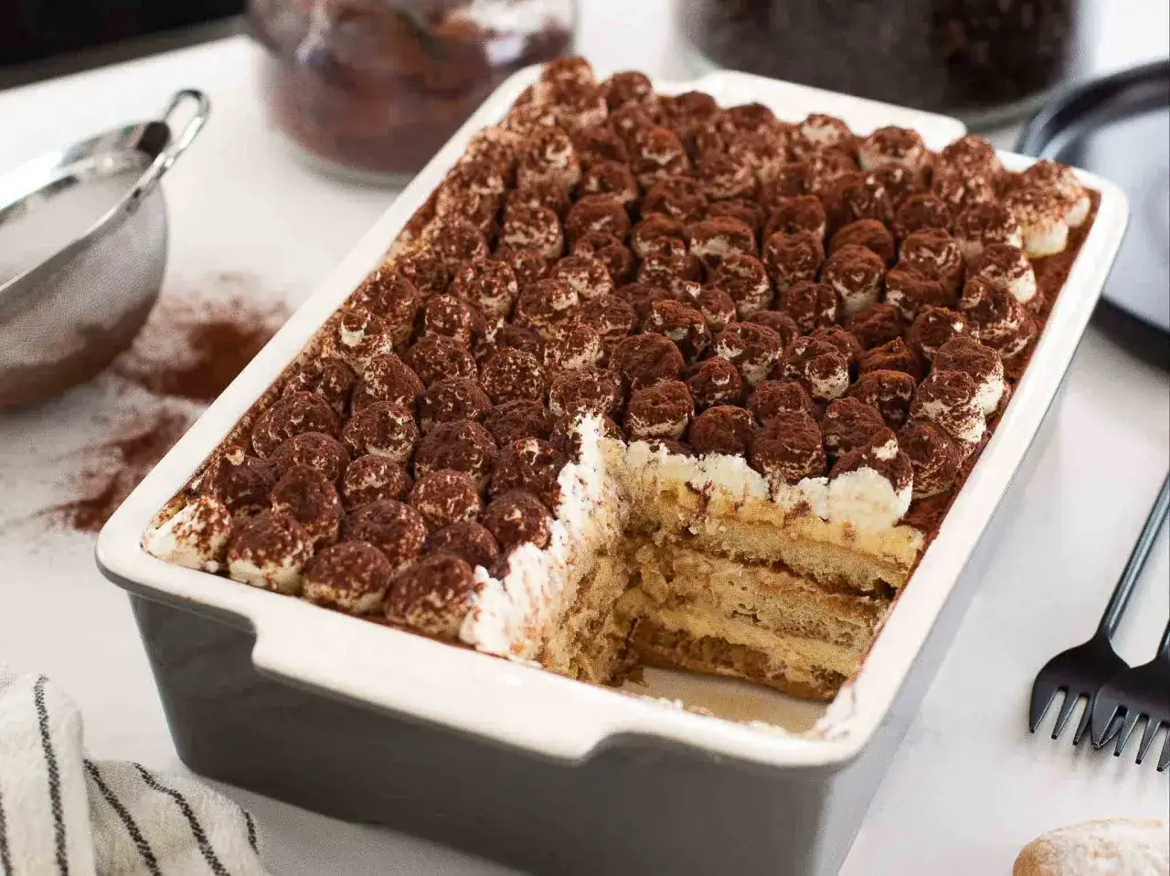 Un délicieux tiramisu pour 4 personnes, généreusement saupoudré de cacao, prêt à être dégusté.